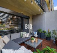 1-IZBOVÝ BYT S VEĽKOU 12 m² TERASOU | SLNEČNICE VILADOMY - Balkón 1-izbového bytu na Fialovej ulici v Bratislave V s posedením a rastlinami.