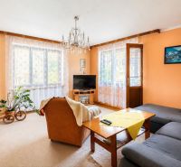 3-IZBOVÝ BYT 90 m² V RODINNOM DOME | POVAŽSKÝ CHLMEC - Žilina - Obývacia izba s krémovými stenami, oranžovým kreslom a šedou sedačkou v rodinnom dome.