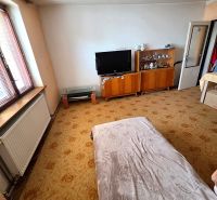 3-IZBOVÝ BYT 90 m² V RODINNOM DOME | POVAŽSKÝ CHLMEC - Žilina - Obývacia izba v rodinnom dome s televízorom, vitrínami a dekoratívnym kobercom.