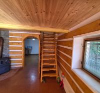 Víkendová chalupa Mikušovce, pozemok 281m2 - Drevené schodisko, sporák a kamenný obklad v rodinnom dome s podlahou s dreveným dekorom.