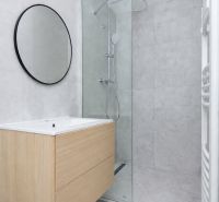 NA PREDAJ-3-IZBOVÝ BYT-NOVÁ REKONŠTRUKCIA-UL.POKROKU-KOŠICE-ZÁPAD - Kúpeľňa v 3-izbovom byte s moderným sprchovým kútom a dreveným dekorom na skrinke.