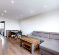 BENADOVA - 4-IZBOVÝ BYT PO KOMPLETNEJ REKONŠTRUKCII, 79 m², LOGGIA  - Obývačka so sedačkou, jedálenským stolom a podlahou s dreveným dekorom v 4-izbovom byte.