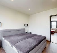 BENADOVA - 4-IZBOVÝ BYT PO KOMPLETNEJ REKONŠTRUKCII, 79 m², LOGGIA  - Svetlá spálňa s posteľou a podlahou s dreveným dekorom v 4-izbovom byte.