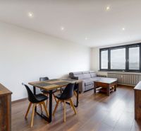 BENADOVA - 4-IZBOVÝ BYT PO KOMPLETNEJ REKONŠTRUKCII, 79 m², LOGGIA  - Obývacia izba so sedením, stolom a podlahou s dreveným dekorom v 4-izbovom byte.