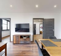 BENADOVA - 4-IZBOVÝ BYT PO KOMPLETNEJ REKONŠTRUKCII, 79 m², LOGGIA  - Interiér 4-izbového bytu s dreveným dekorom podlahy, televízorom a dreveným nábytkom.