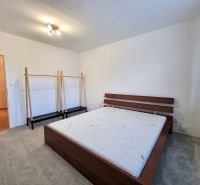 PRENÁJOM - 2 izbový byt Nitra - Chrenová - Spálňa s posteľou a vešiakom v 2-izbovom byte, podlaha s dreveným dekorom.