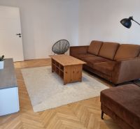 PRENÁJOM - 2 izbový byt Nitra - Chrenová - Obývacia izba v 2-izbovom byte, hnedá sedačka, konferenčný stolík, podlaha s dreveným dekorom.