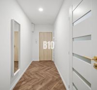 Prémiové bývanie v centre Nitry | 3 izby, veľký balkón - Chodba 3-izbového bytu s podlahou s dreveným dekorom a zrkadlom na stene.