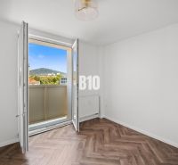 Prémiové bývanie v centre Nitry | 3 izby, veľký balkón - Izba v 3-izbovom byte s výhľadom a podlahou s dreveným dekorom.