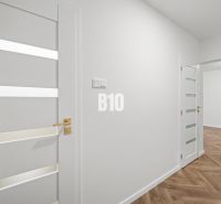 Prémiové bývanie v centre Nitry | 3 izby, veľký balkón - Biely interiér 3-izbového bytu s podlahou s dreveným dekorom a elegantnými dverami.