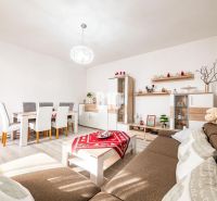 Prerobený dom, 981 m2 pozemok - Chrenová, Nitra (TOP lokalita) - Obývacia izba s jedálenským stolom, podlahou s dreveným dekorom a hnedou sedačkou v rodinnom dome.