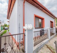 Prerobený dom, 981 m2 pozemok - Chrenová, Nitra (TOP lokalita) - Rodinný dom v Nitre s bielou fasádou, červeným lemovaním a záhradkou.