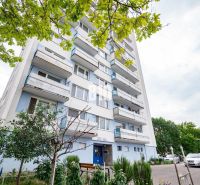 Nový 3 izb. byt s 2x balkónom, Nitra - Chrenová (2026) - Bytový dom v Nitre so stromami a parkoviskom pred 3-izbovým bytom.