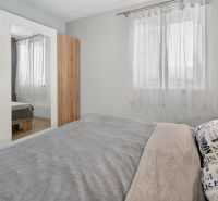 Predaj 2-izbový byt GREEN VILLAGE, loggia, parkovanie, Dunajská Lužná - Spálňa v 2-izbovom byte s posteľou, skriňou a bielymi závesmi na okne.