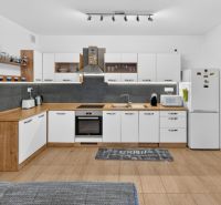 Predaj 2-izbový byt GREEN VILLAGE, loggia, parkovanie, Dunajská Lužná - Kuchyňa v 2-izbovom byte s bielym nábytkom, sivými obkladmi, podlahou s dreveným dekorom.