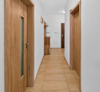 Predaj 2-izbový byt GREEN VILLAGE, loggia, parkovanie, Dunajská Lužná - Chodba v 2-izbovom byte s dreveným nábytkom a podlahou s dreveným dekorom.