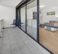 Predaj 2-izbový byt GREEN VILLAGE, loggia, parkovanie, Dunajská Lužná - Priestranný balkón 2-izbového bytu s výhľadom na interiér obývačky, podlaha s dekórom.