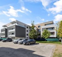 Predaj 2-izbový byt GREEN VILLAGE, loggia, parkovanie, Dunajská Lužná - Bytové domy na Orechovej ulici v Dunajskej Lužnej so zaparkovanými autami a zeleňou.