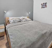 Predaj 2-izbový byt GREEN VILLAGE, loggia, parkovanie, Dunajská Lužná - Spálňa s posteľou a nočným stolíkom, 2-izbový byt, podlaha s dreveným dekorom.