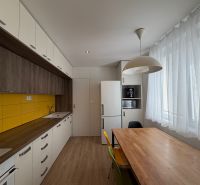Exkl. moderný, priestranný 3 iz byt s lódžiou v Piešťanoch REZERVOVANÝ - Kuchyňa s podlahou s dreveným dekorom, žltým obkladom a jedálenským stolom v 3-izbovom byte.