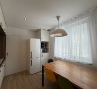 Exkl. moderný, priestranný 3 iz byt s lódžiou v Piešťanoch REZERVOVANÝ - Kuchyňa s bielou chladničkou, farebnými stoličkami a podlahou s dreveným dekorom v 3-izbovom byte.