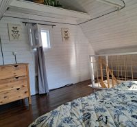 ZĽAVA! Čarovná chata v Malých Karpatoch na slnečnom pozemku - Interiér chaty s posteľou a skrinkou, podlaha s dreveným dekorom.