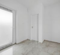 Moderný rodinný dom, ktorý vás prekvapí priestorom aj atmosférou - Biela vstupná miestnosť v Rodinnom dome s dlažbou a dverami.