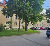 Kompletne zrekonštruovaný 3-izbový byt na Študentskej ulici v Trnave - Parkovisko pri 3-izbových bytoch na Študentskej ulici v Trnave, obklopené zeleňou a stromami.
