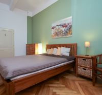 LAURINSKÁ, 2i byt, 68m² – REPREZENTATÍVNE bývanie v historickom CENTRE - Spálňa v 2-izbovom byte s posteľou, kreslom a podlahou s dreveným dekorom.