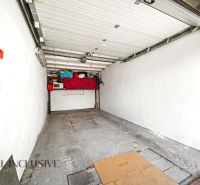 Na predaj veľkom. 3-i. byt s balk. v centre Dun.Stredy - Garáž s otvorenými dverami a regálmi na úložný priestor. Podlaha z betónu.