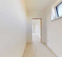 Skolaudovaný 4 izbový RD bungalov 101,65 m2 na pozemku 531 m2, Senec - Úzka chodba v Rodinnom dome s bielymi stenami a strešným oknom.