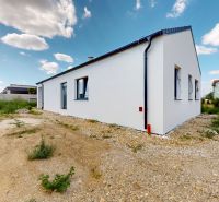Skolaudovaný 4 izbový RD bungalov 101,65 m2 na pozemku 531 m2, Senec - Rodinný dom na Karasovej ulici v Senci obklopený zelenou vegetáciou a modrou oblohou.