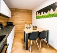 Investičný APARTMÁN v centre Terchovej - Interiér Rekreačného apartmánu s kuchyňou, jedálenským stolom a podlahou s dreveným dekorom.