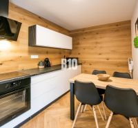 Investičný APARTMÁN v centre Terchovej - Kuchyňa v Rekreačnom apartmáne s podlahou s dreveným dekorom a štýlovým nábytkom.