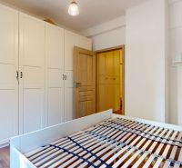 Priestranný 2i byt v obklopení zelene len pár krokov od OC Nivy | 53m² - Spálňa v 2-izbovom byte s bielymi skriňami a podlahou s dreveným dekorom.