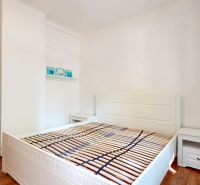 Priestranný 2i byt v obklopení zelene len pár krokov od OC Nivy | 53m² - Spálňa v 2-izbovom byte s podlahou s dreveným dekorom, bielou posteľou a nočným stolíkom.