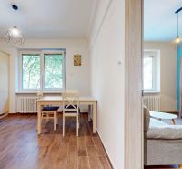 Priestranný 2i byt v obklopení zelene len pár krokov od OC Nivy | 53m² - Kuchyňa s jedálenským stolom a obývačka s podlahou s dreveným dekorom v 2-izbovom byte.