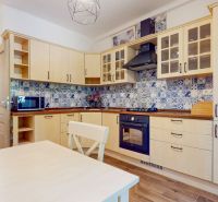 Priestranný 2i byt v obklopení zelene len pár krokov od OC Nivy | 53m² - Kuchyňa v 2-izbovom byte s drevenými skrinkami, modrými obkladmi a podlahou s dreveným dekorom.
