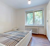 Priestranný 2i byt v obklopení zelene len pár krokov od OC Nivy | 53m² - Svetlá spálňa s bielym posteľným rámom, skriňou a podlahou s dreveným dekorom.