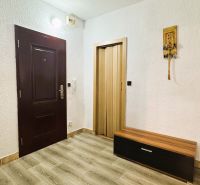 94,66 m², štyri izby a nikto nad hlavou. A Komenského má svoje výhody! - Interiér 4-izbového bytu s bielymi stenami, podlahou s dreveným dekorom a tmavými dverami.