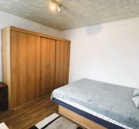 94,66 m², štyri izby a nikto nad hlavou. A Komenského má svoje výhody! - Spálňa v 4-izbovom byte s posteľou, skriňou a podlahou s dreveným dekorom.