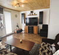 94,66 m², štyri izby a nikto nad hlavou. A Komenského má svoje výhody! - Obývacia izba v 4-izbovom byte s podlahou s dreveným dekorom a televízorom na stene.