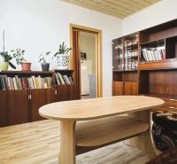 94,66 m², štyri izby a nikto nad hlavou. A Komenského má svoje výhody! - Obývačka so skriňami, knihami, kvetmi a podlahou s dreveným dekorom v 4-izbovom byte.