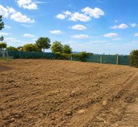 NA PREDAJ – rovinatý stavebný pozemok v Pravoticiach | 660 m² - Pozemky na bývanie v Pravoticiach s obrábanou pôdou, zeleným plotom a modrou oblohou.