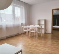 Prenájom dvoch 2-izbových bytov vedľa seba, Martin - centrum - 2-izbový byt s podlahou s dreveným dekorom, biely stôl s priehľadnými závesmi.