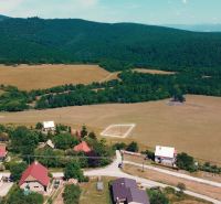 POZEMOK NA VÝSTAVBU PODHRADIE - Vidiecky pohľad na pozemky na bývanie v Podhradí obklopené lesmi a lúkami.