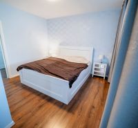 Na predaj 5i rodinný dom, novostavba, Vráble, pozemok 1200m2 - Spálňa v rodinnom dome s posteľou, nočnými stolíkmi a podlahou s dreveným dekorom.