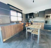 MODERNÁ VILA 3+1 S VÝHĽADOM NA MORE A HORY | YENİ BOĞAZİÇİ, - Kuchyňa s dreveným dekorom, moderné spotrebiče, priestranný stôl a sivé skrinky.