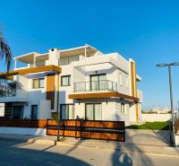 MODERNÁ VILA 3+1 S VÝHĽADOM NA MORE A HORY | YENİ BOĞAZİÇİ, - Rodinný dom v Yeni Boğaziçi s bielou fasádou, drevenými prvkami a palmami na pozemku.