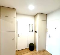 Na predaj úplne nový 1i byt od architekta v tichej časti Dúbravky - Vstupná hala s podlahou s dreveným dekorom a bielymi skriňami v 1-izbovom byte.